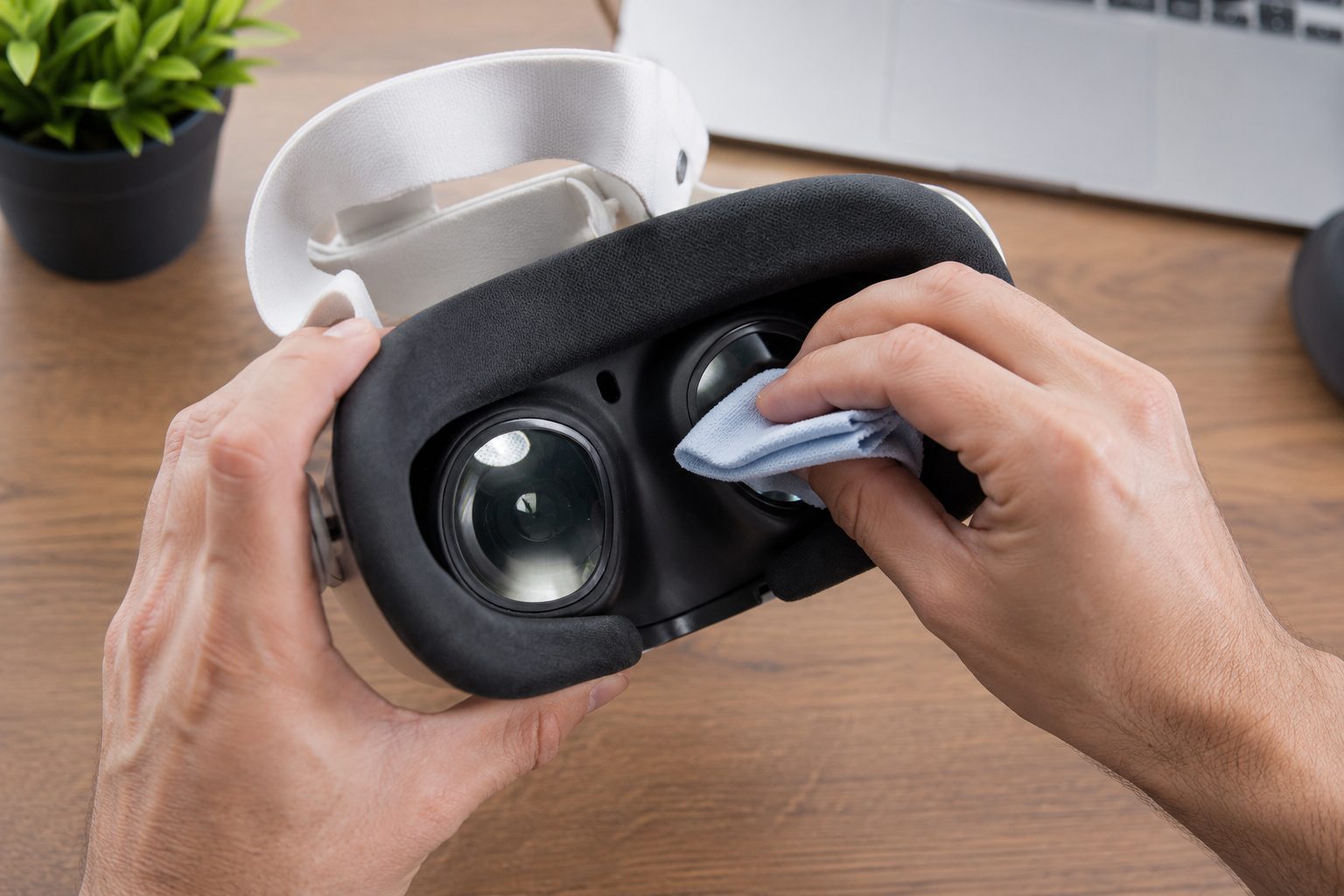 Hands cleaning a VR headset's lenses with a microfiber cloth